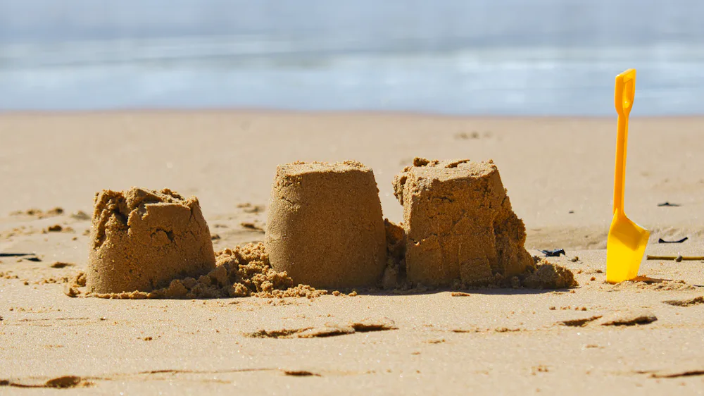 Sand castles and a toy shovel on the beach